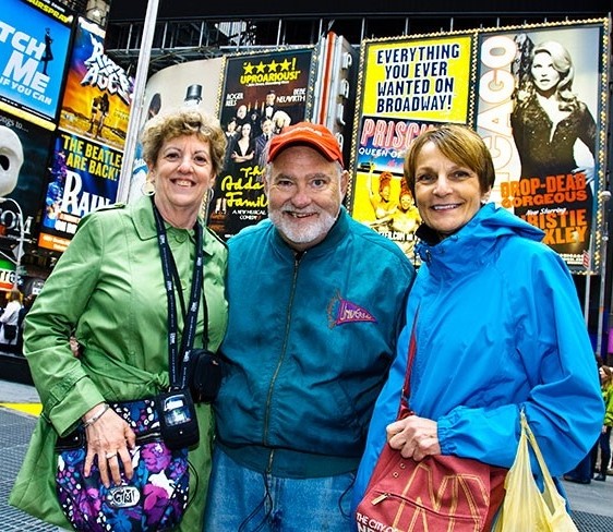 3 older adults smiling and standing in Times Square in New York City