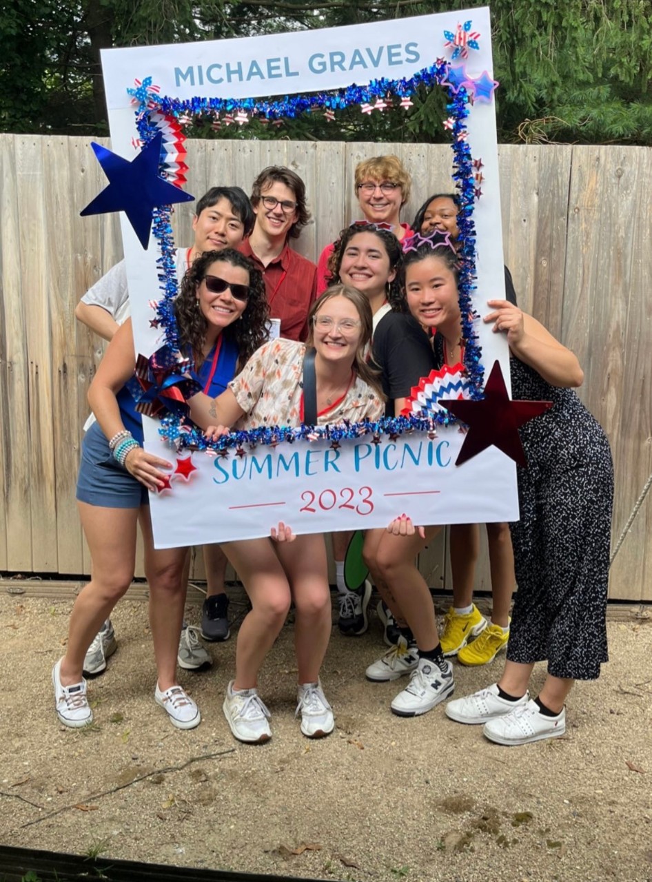 co-op students posing inside a large cardboard picture frame that reads Michael Graves Summer Picnic 2023