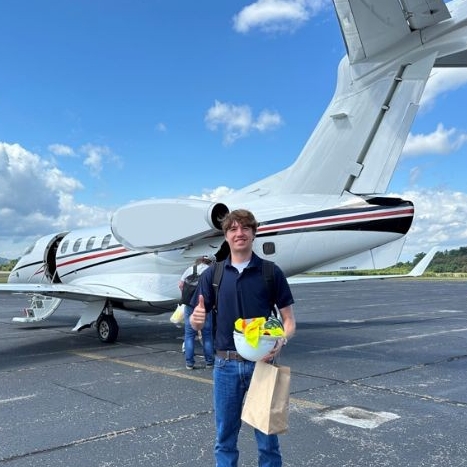 A co-op student stands in front of an airplane.